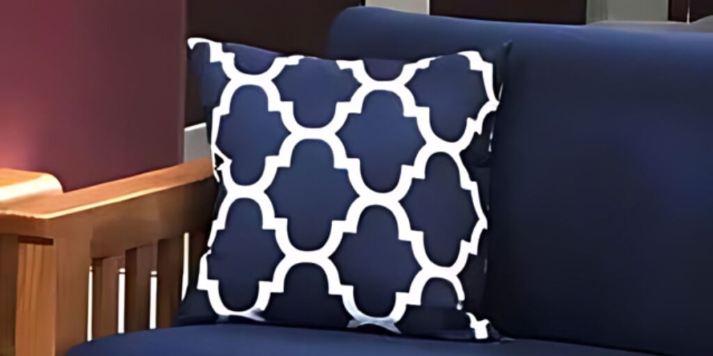 A blue couch with a white and navy patterned pillow, adding a touch of elegance to the room.