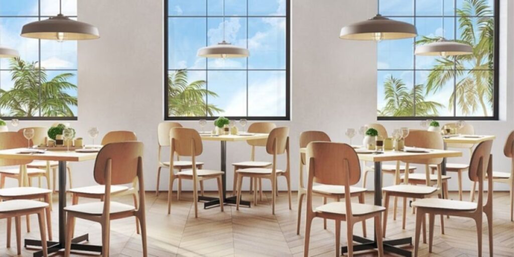 A restaurant with tables and chairs set up in front of large windows, offering a bright and inviting dining space.