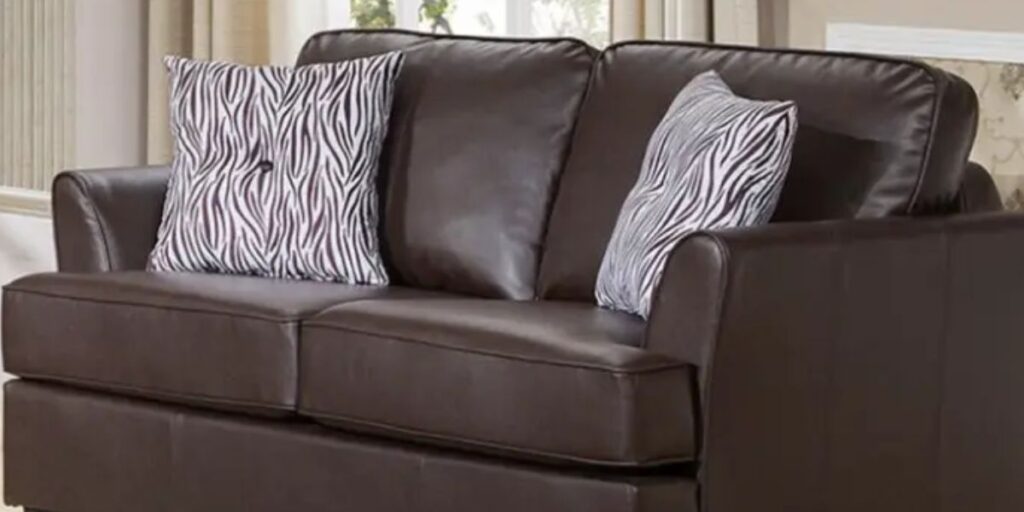A brown leather sofa with decorative pillows resting on it, creating a cozy and inviting atmosphere.