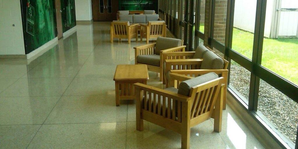 Bariatric chairs in a long hallway with wooden chairs and tables, ensuring safety and comfort for patients and healthcare teams.