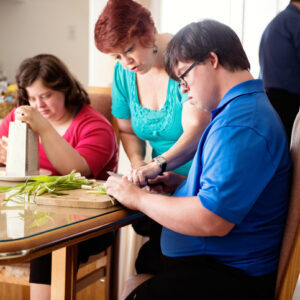 Couple with Down Syndrome learning cooking cutting vegetables